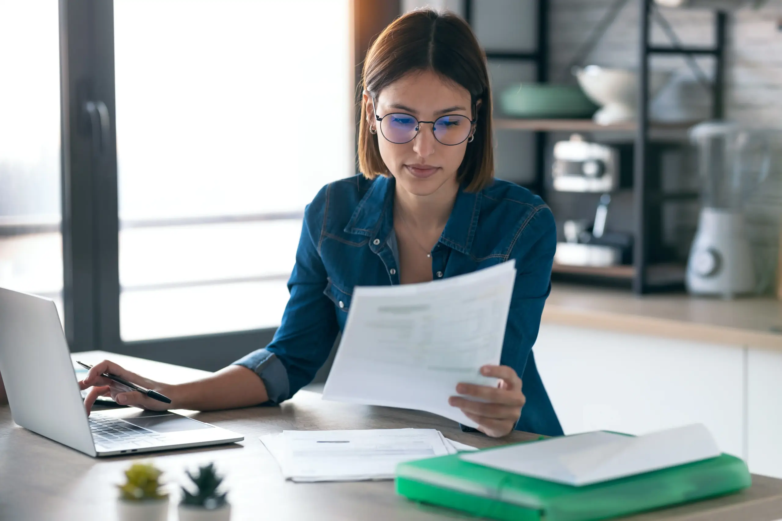 Woman doing paperwork at laptop